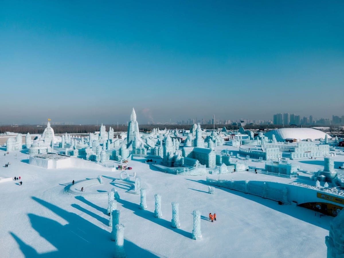 Aerial view of the ice buildings at Harbin Ice-Snow World with the city skyline behind