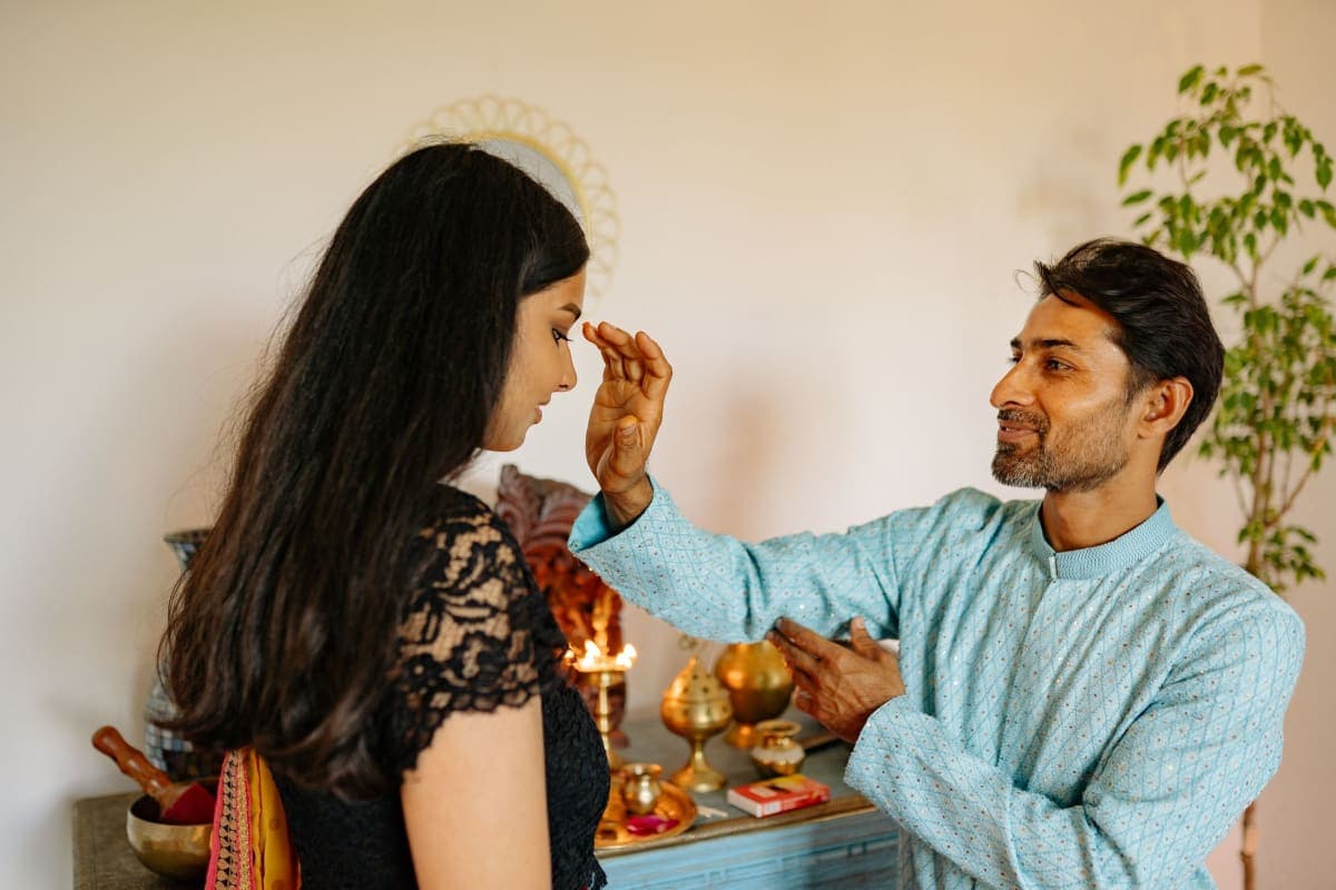 A couple performing a traditional Diwali ceremony with oil lamps at home