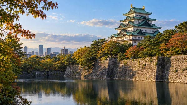Nagoya Castle with green roofs and golden shachihoko above its stone walls and moat in early autumn